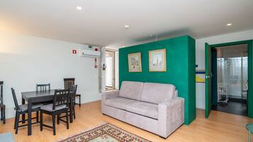 Une pièce comprenant une table à manger, des chaises, un canapé, un tapis à motifs et un mur d’accent vert.
