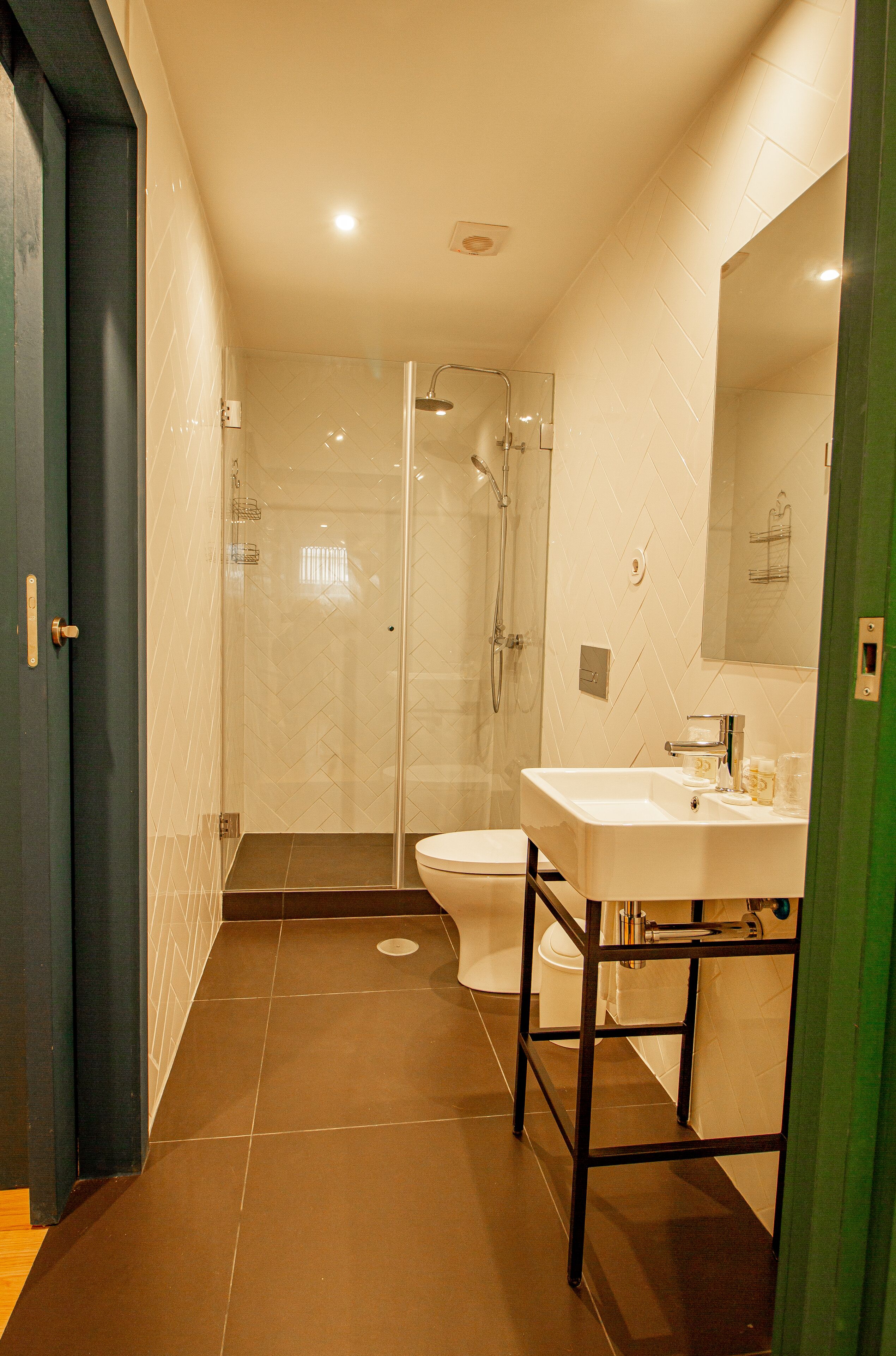 A modern bathroom with a glass-enclosed shower, a white sink, and a toilet.