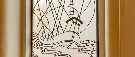 A decorative window with a maritime theme, including a ship and waves.