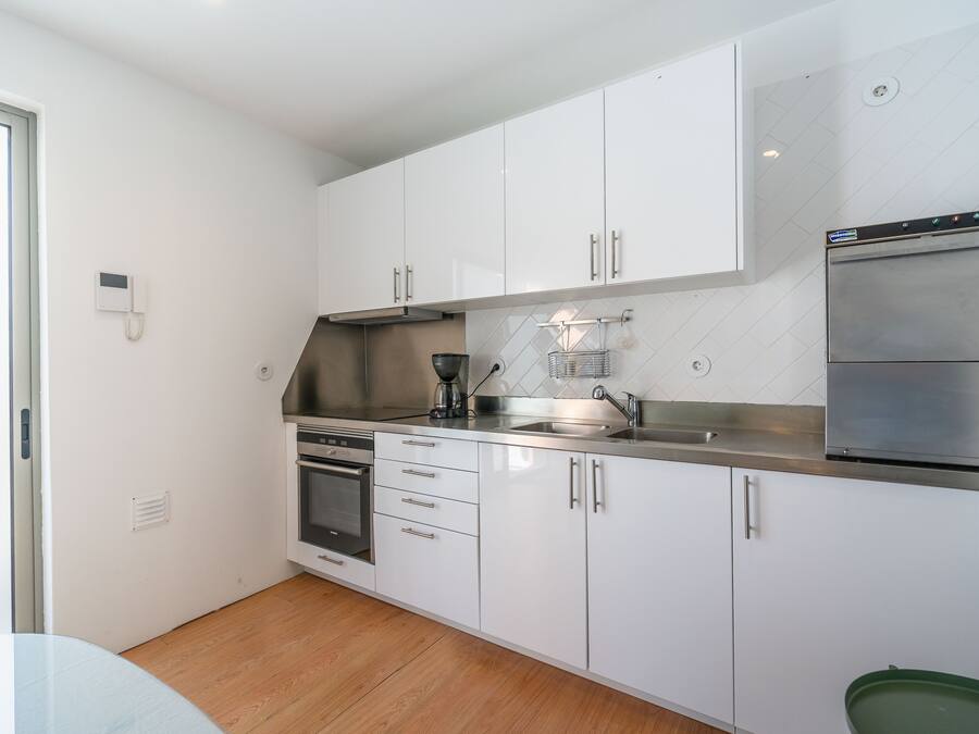 A modern kitchen with white cabinets, stainless steel appliances, and a tiled backsplash.