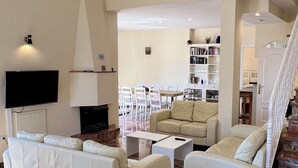 Una sala de estar con un juego de sofá, una mesa de centro y un televisor. Una escalera conduce a otro nivel.