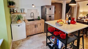 Une cuisine de taille réduite comprenant un évier, un réfrigérateur et un coin repas avec une table et des chaises.