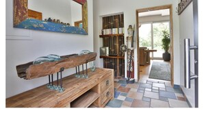 Un couloir avec un banc en bois, un miroir et une bibliothèque.