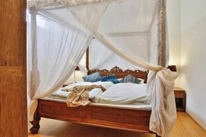 A wooden four-poster bed with a canopy, white bedding, and decorative pillows. - Apartment "BALI" with an exotic Asian flair (Attendorfberg)