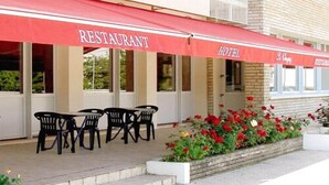 A restaurant and hotel with outdoor seating and red awnings. - Le Chagny Hotel (Chagny)