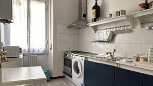 A modern kitchen with a built-in washing machine, a stove, and a window with curtains.