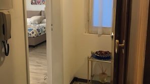 A hallway with a door leading to a bedroom, a small table with a bowl, and a wall with colorful circular patterns.