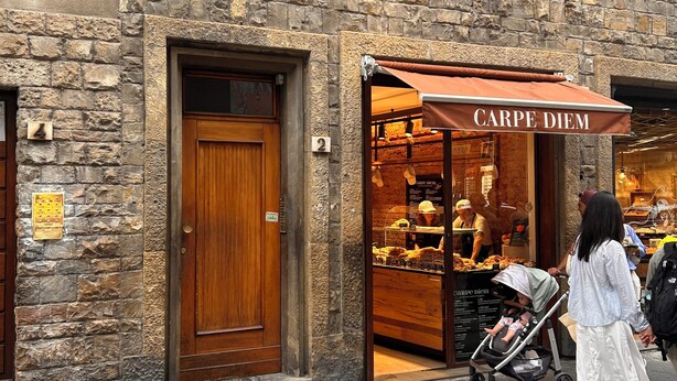 A stone building with a wooden door and a shop entrance labeled 'CARPE DIEM.'