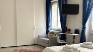 A bedroom with a bed, a desk, a chair, a TV, and a wardrobe.