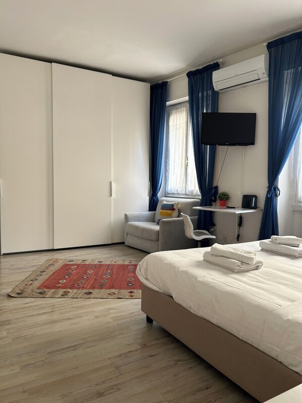 A bedroom with a bed, a desk, a chair, a TV, and a wardrobe.