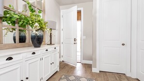 A hallway with white cabinetry, a large vase with flowers, and a patterned rug. - Desert Escape at Ladera (Washington)