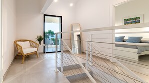 Relax in a stylish space with a sofa, wicker chair, and potted plant, surrounded by a large mirror and artwork.
