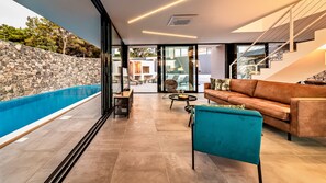Uma sala de estar moderna com piscina, parede de pedra e escadaria.