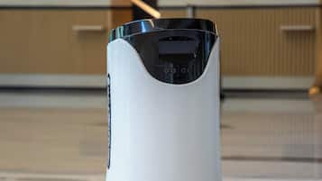 Un robot in un'elegante hall con luci a soffitto geometriche e pavimento lucido.