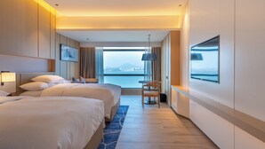 Hotelkamer met twee bedden, een groot raam en uitzicht op de stad, een bureau en een stoel.