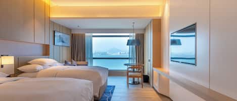 Habitación de hotel con dos camas, un ventanal con vista a la ciudad, un escritorio y una silla.