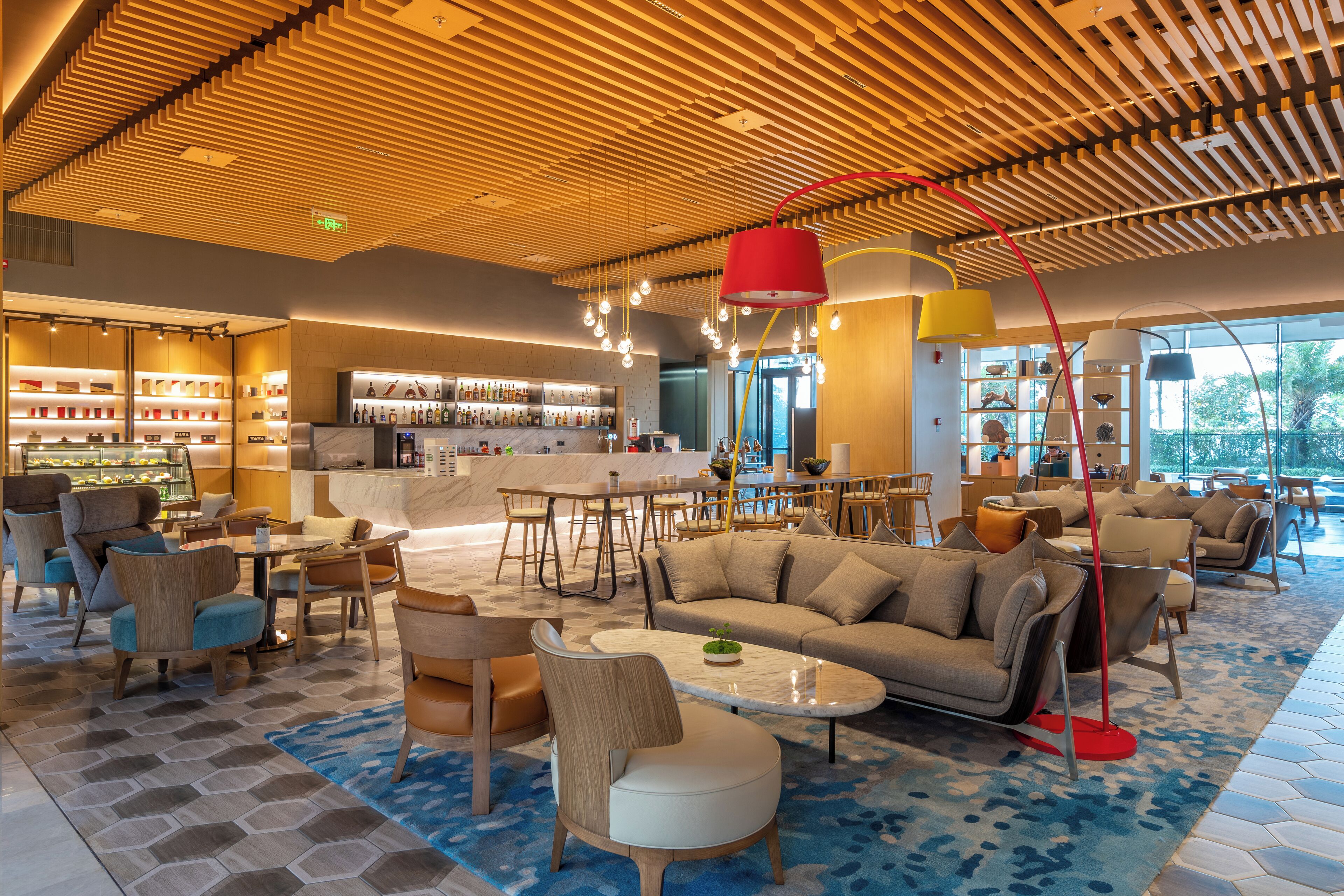 Un moderno vestíbulo de hotel con bar, zonas de estar y vistas al exterior.