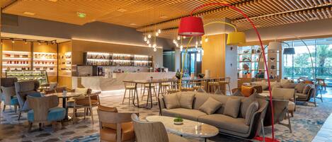 Un moderno vestíbulo de hotel con bar, zonas de estar y vistas al exterior.