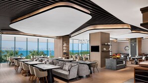 A modern restaurant with a high ceiling, large windows, and a view of the ocean. - Courtyard by Marriott Xiamen (Xiamen)