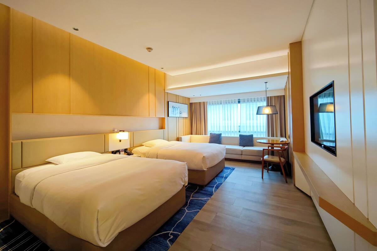 Een hotelkamer met twee bedden, een bank, een bureau en een televisie.