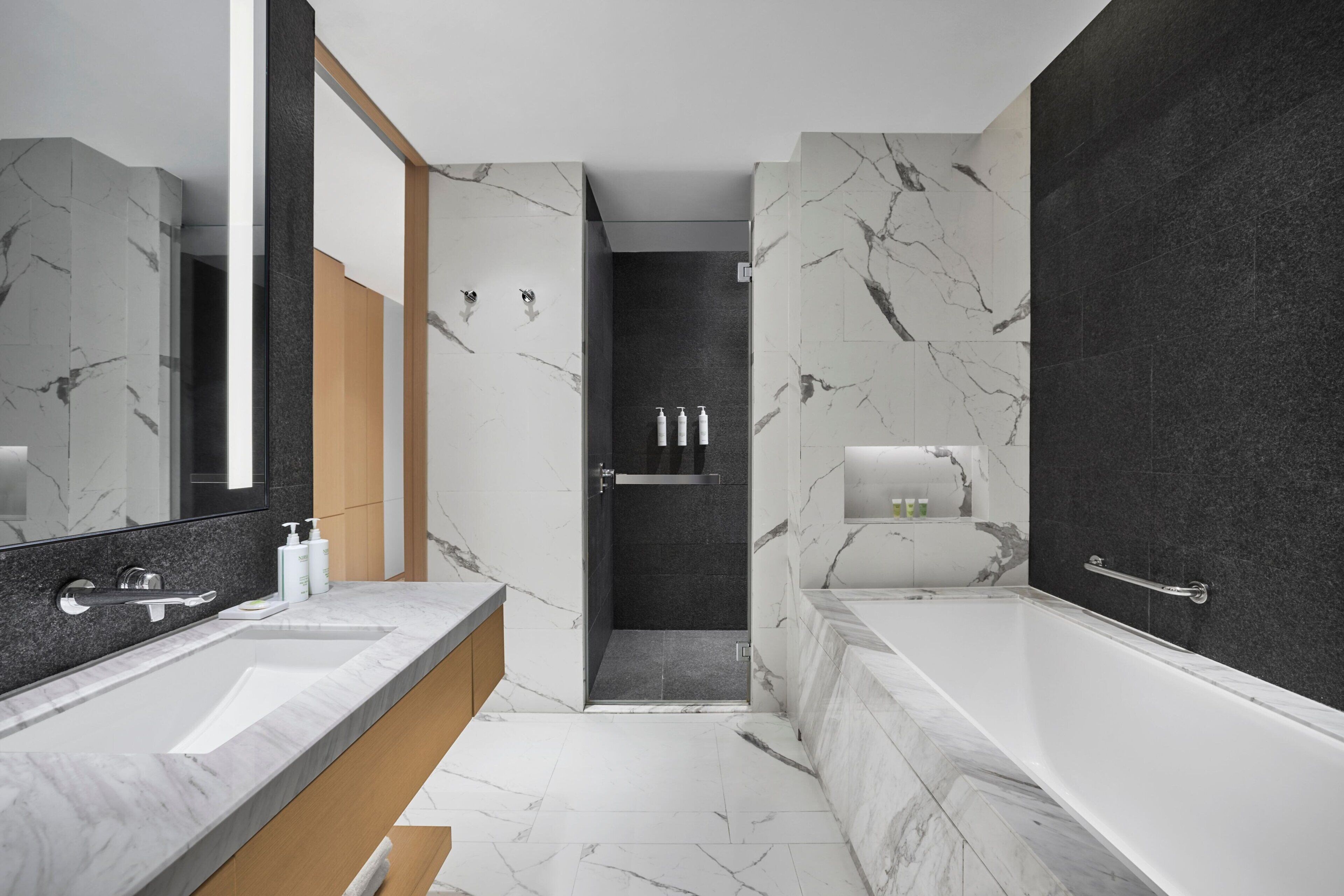 Une salle de bain moderne avec un grand miroir, une baignoire et un espace douche.