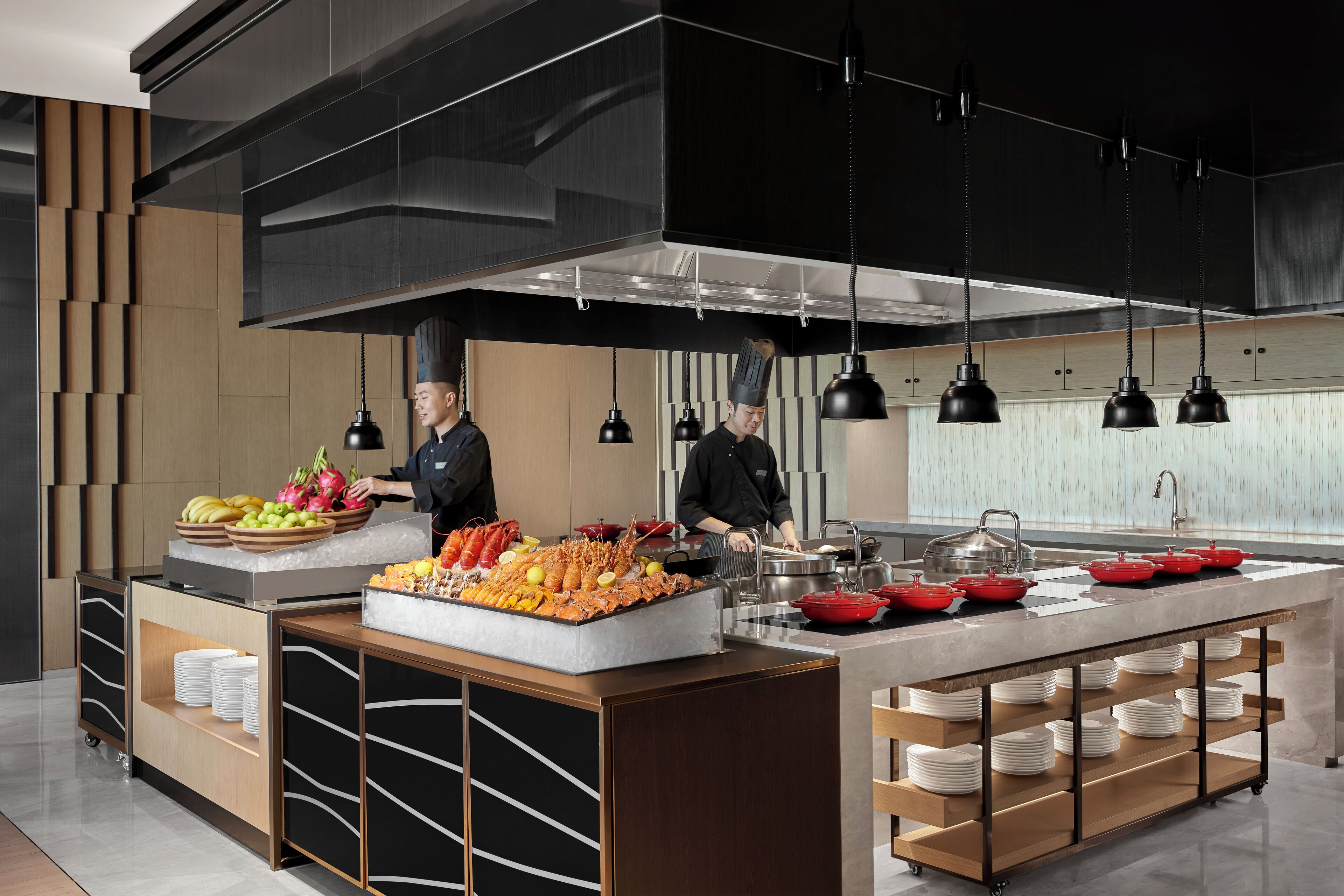 A modern kitchen with a central island, a buffet setup, and a chef preparing food.