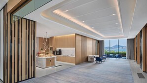 Een moderne hotellobby met een receptiebalie, een zithoek en grote ramen met uitzicht op de stad.