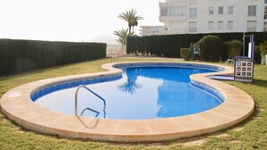 A swimming pool with a tiled edge, surrounded by a grassy area and a hedge. - Athena beauty in Altea (Altea)