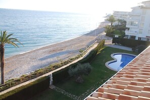 Vista de una playa con piscina y un edificio con balcones.