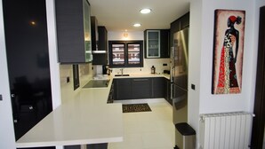 A modern kitchen with dark cabinets, a white countertop, and a black trash bin. - Athena beauty in Altea (Altea)