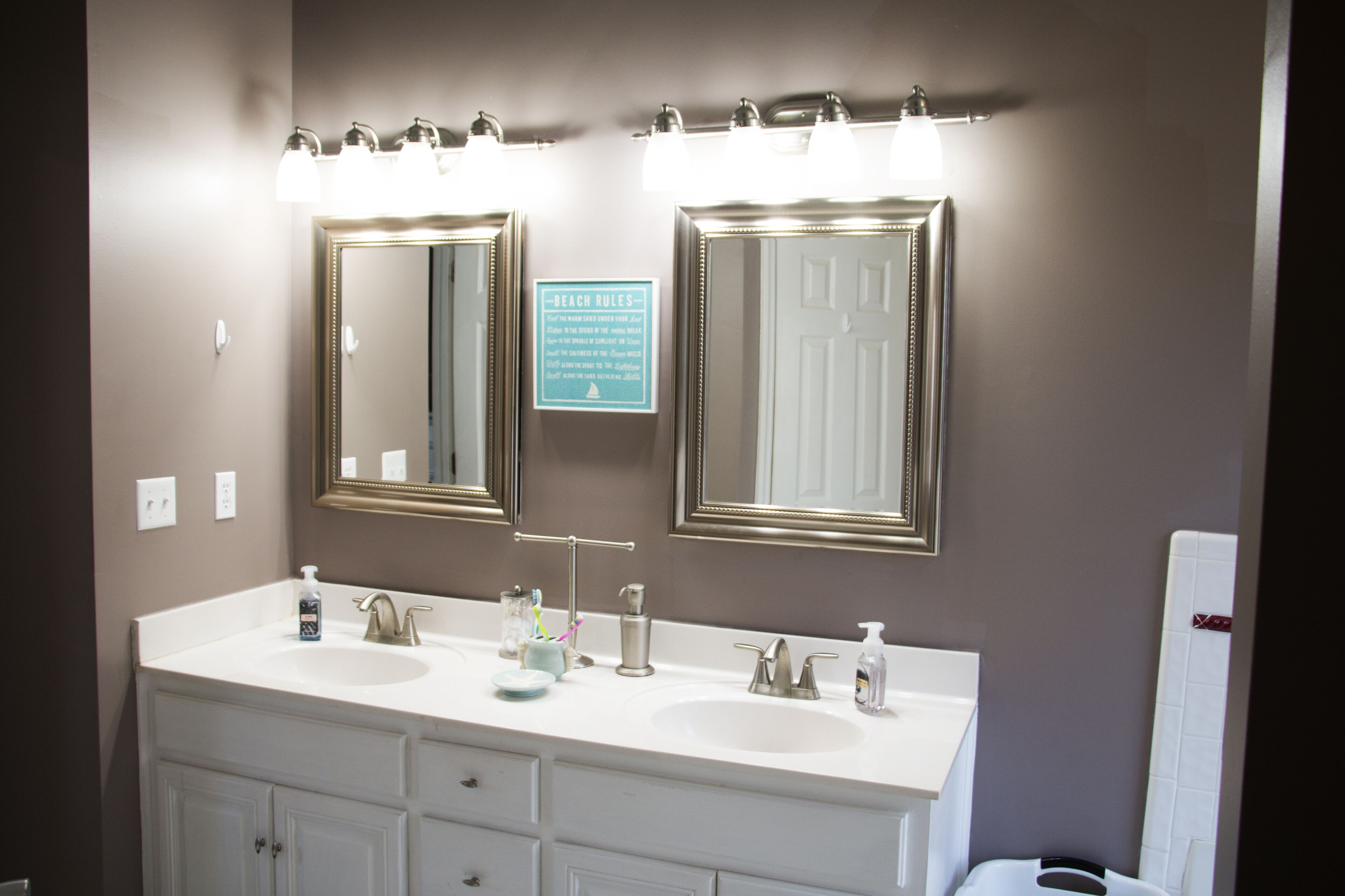 A bathroom with two sinks, a mirror, and a sign with text.