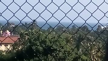 A chain-link fence with a view of a house and trees in the background.