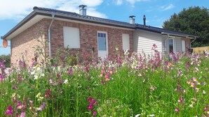 Ein Ziegelhaus mit einer Garagentür, umgeben von einem Feld voller Wildblumen.