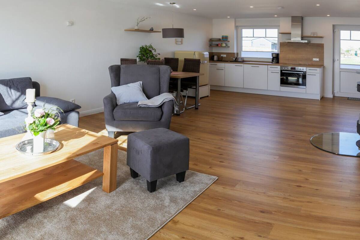 Uma sala de estar moderna com um sofá cinzento, uma mesa de centro de madeira e uma poltrona cinzenta.
