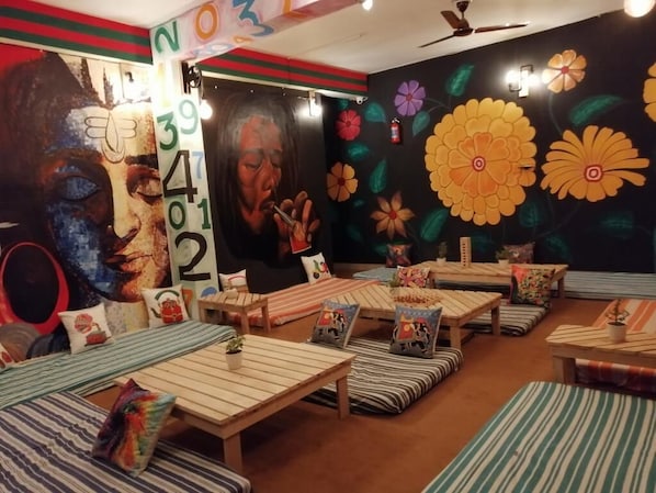 A room with multiple seating areas, including tables and benches, with colorful floral wall art and a large number display.