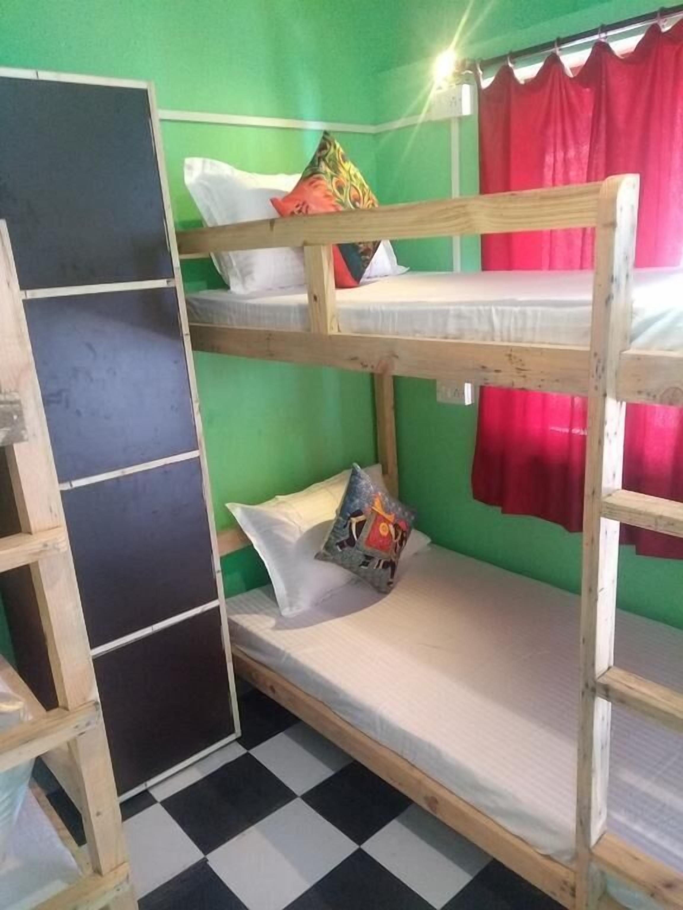 A bunk bed room with green walls, a checkered floor, and a red curtain.