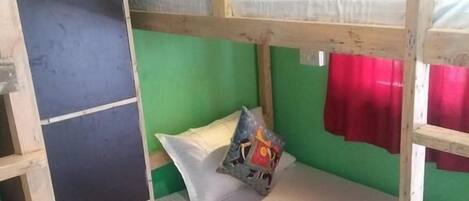 A bunk bed room with green walls, a checkered floor, and a red curtain.