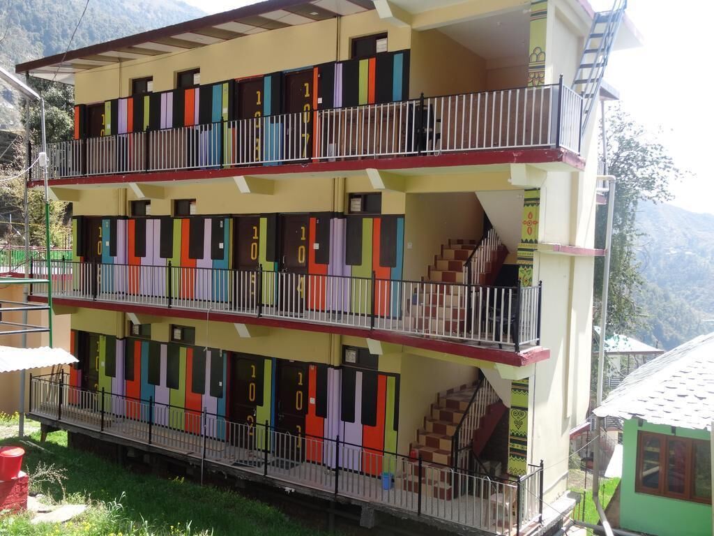 A multi-story building with colorful doorways, balconies, and a staircase.