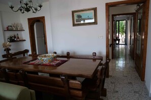 Un comedor con una mesa y sillas de madera, un cuenco floral y un cuadro en la pared.