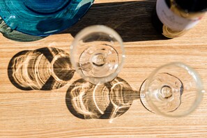 Three wine glasses on a wooden surface with a blue object and a bottle in the background. - Nautilus Charm Apartment (Chania)