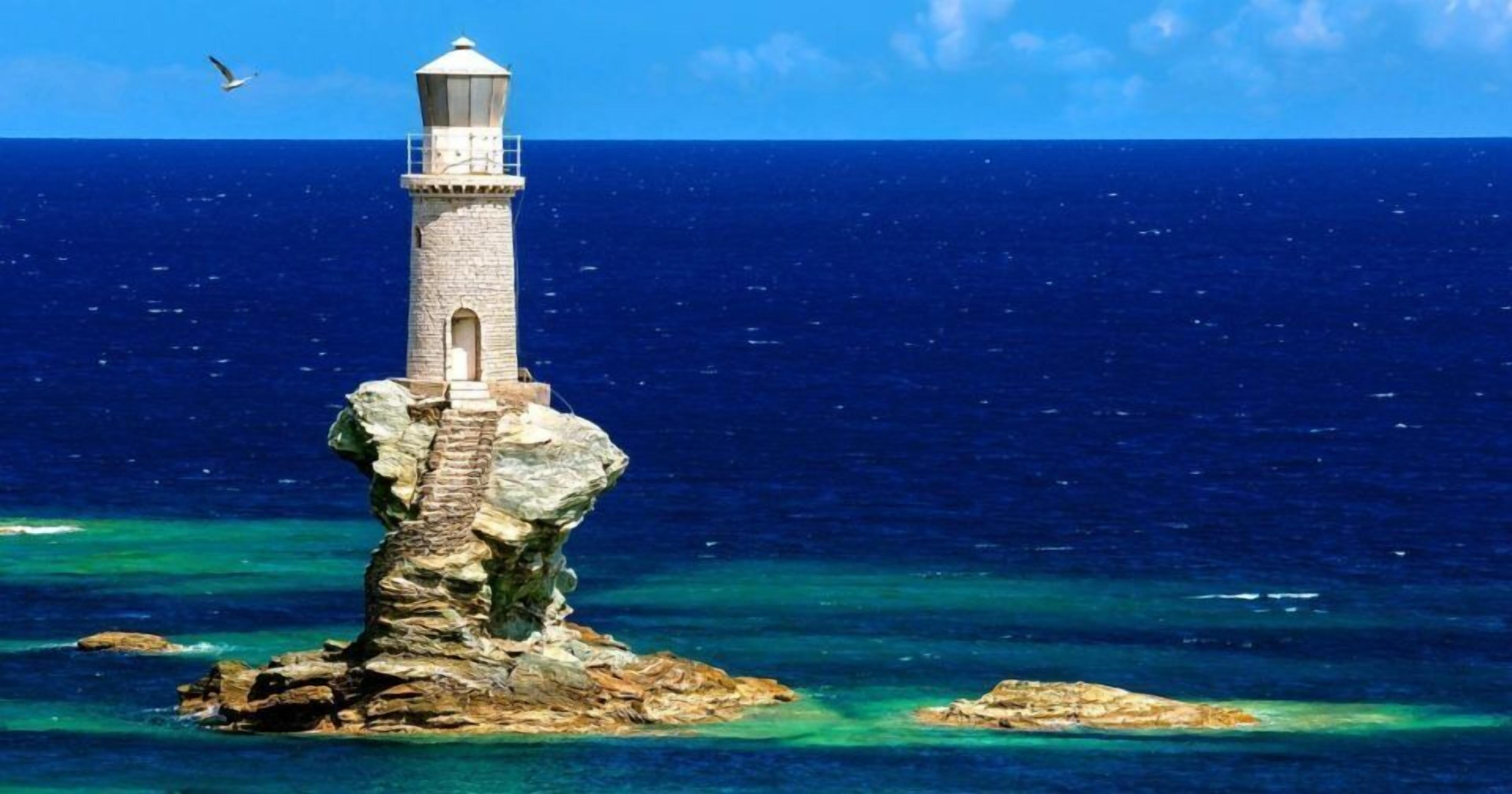 Un faro en un promontorio rocoso con aguas azul cristalino y una gaviota volando cerca.
