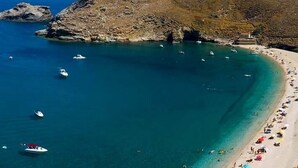Vue aérienne d’une zone côtière avec une plage, des bateaux et un terrain rocheux.
