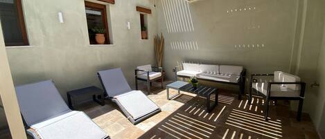 A sunlit patio with two lounge chairs, a sofa, and a small table.