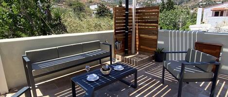 An outdoor patio area with a wooden pergola, a table set with plates and glasses, and a bench.