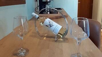 Una mesa de madera con dos copas de vino y una botella. Hay una cafetera sobre la mesa.