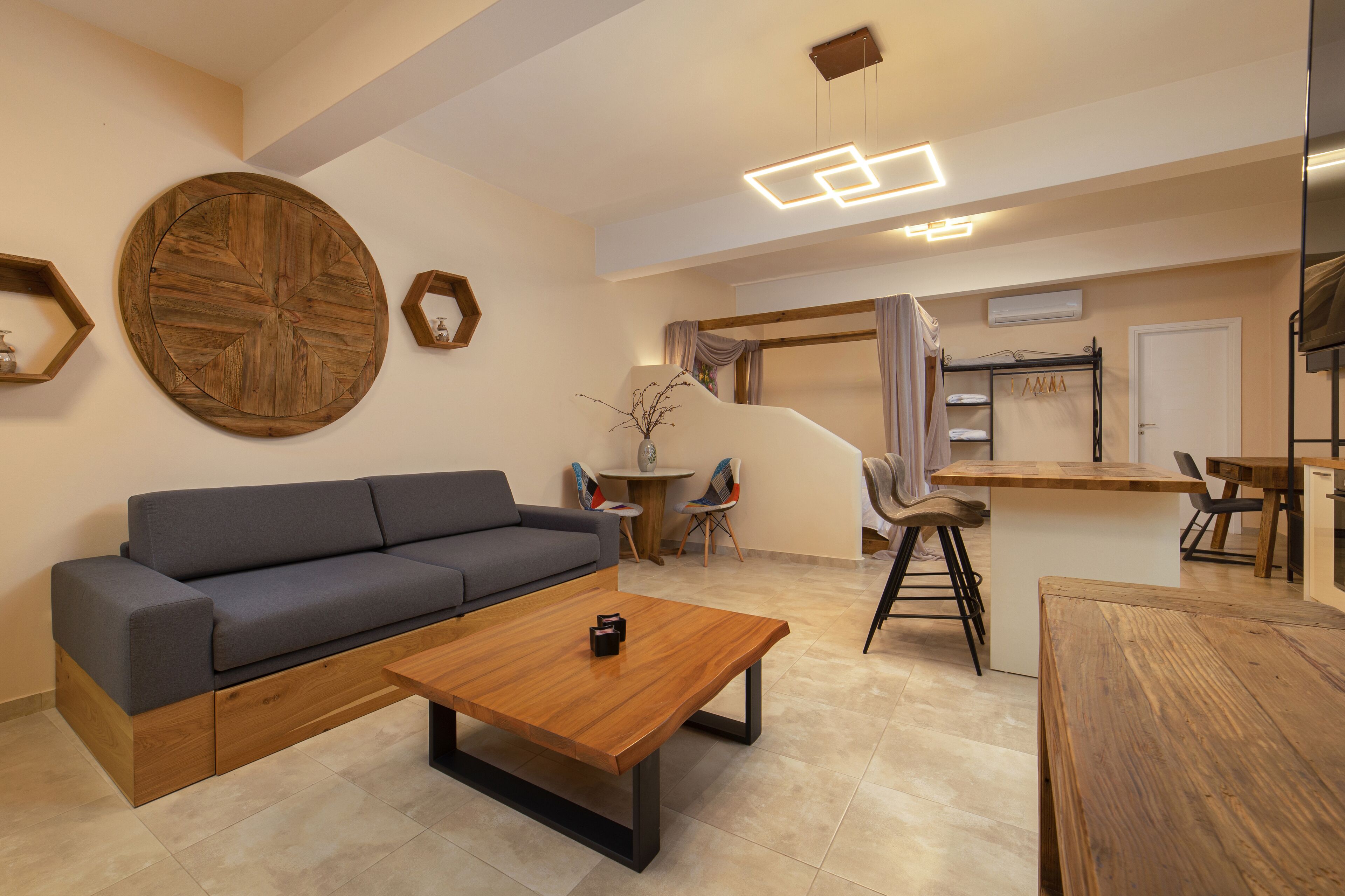 A modern living room with a grey sofa, wooden coffee table, and a dining area with a wooden table and chairs.