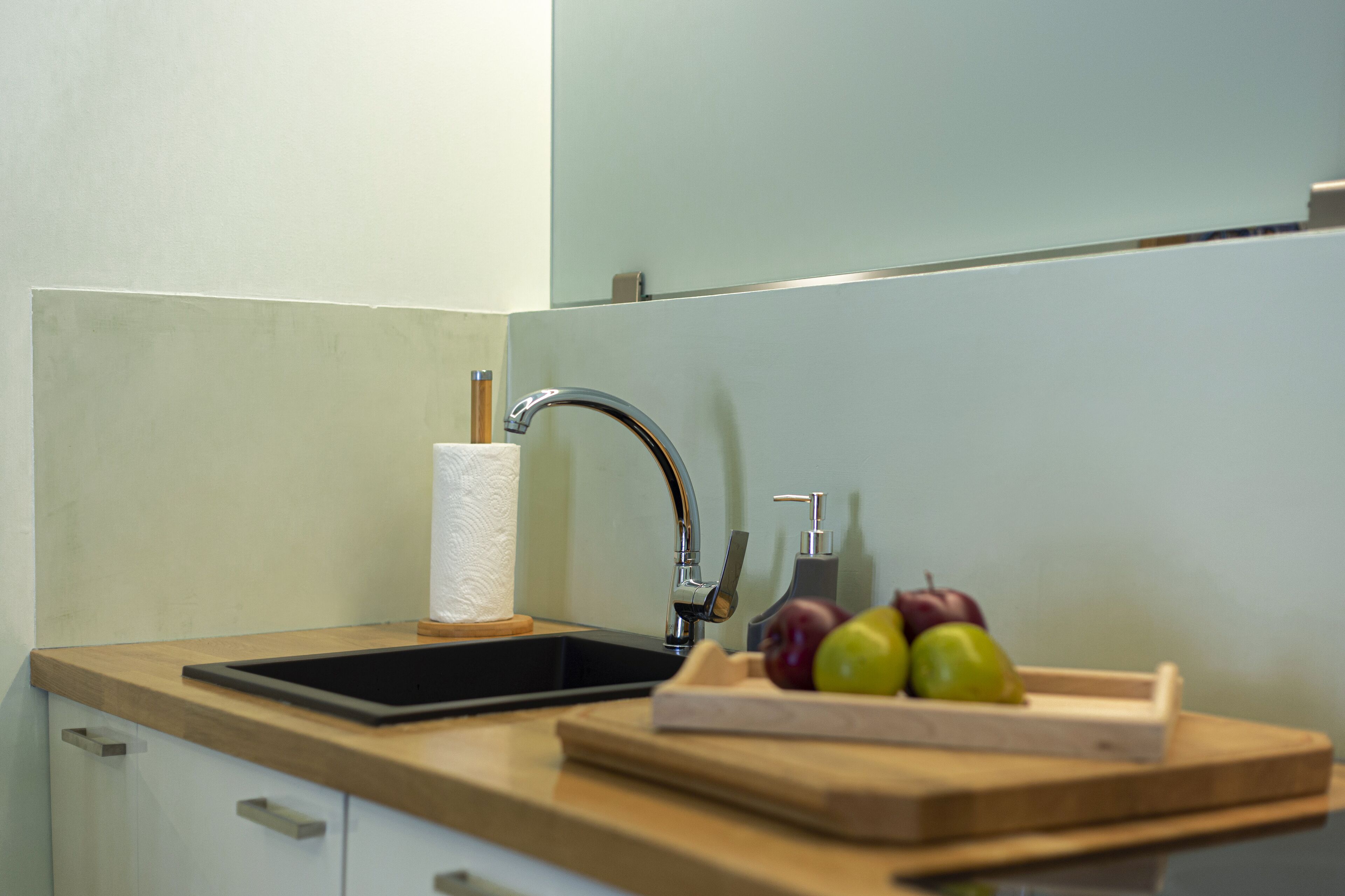 A kitchen with a sink, countertop, and a wooden cutting board with apples.