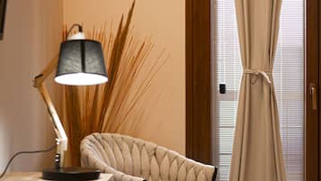 A room with a desk, a chair, a lamp, and a window with curtains.