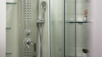 Eine moderne Dusche mit Glasabtrennung, einem Glastablett mit Topfpflanze und einer Glasduschtür.