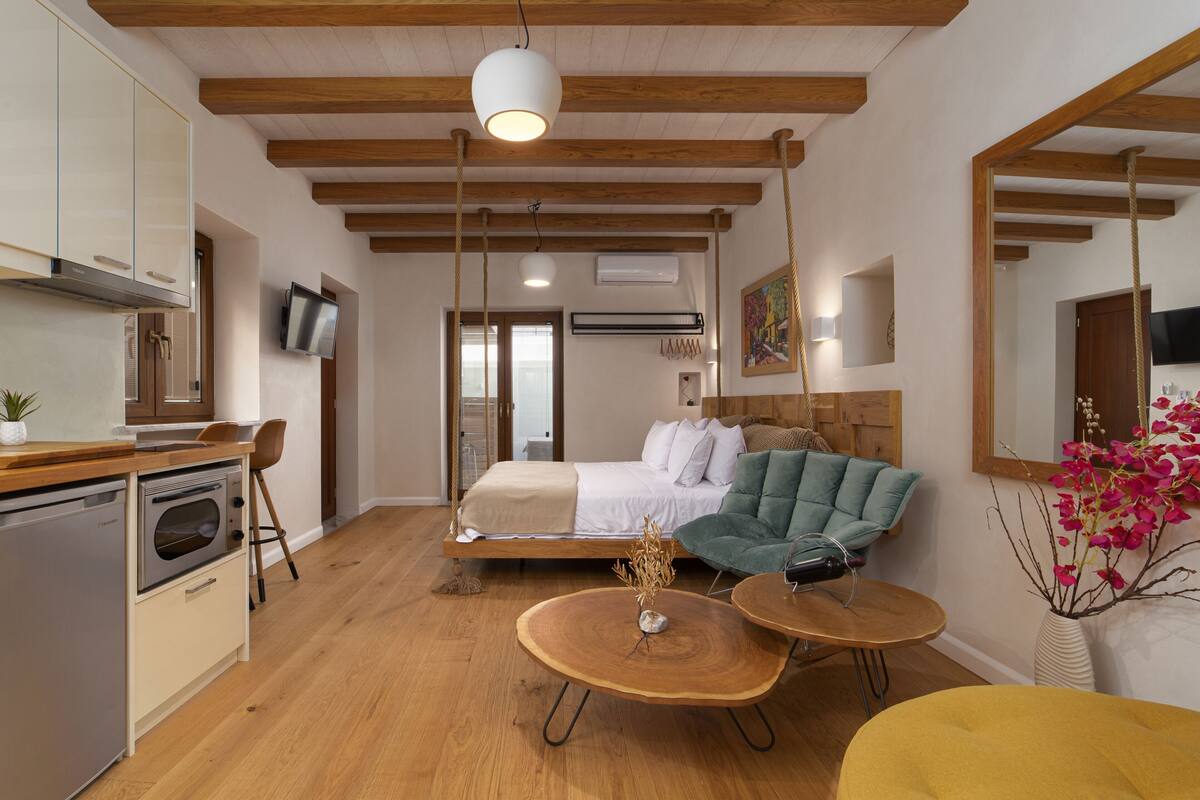 A modern interior with a kitchen, dining area, and a bed with a swing chair.